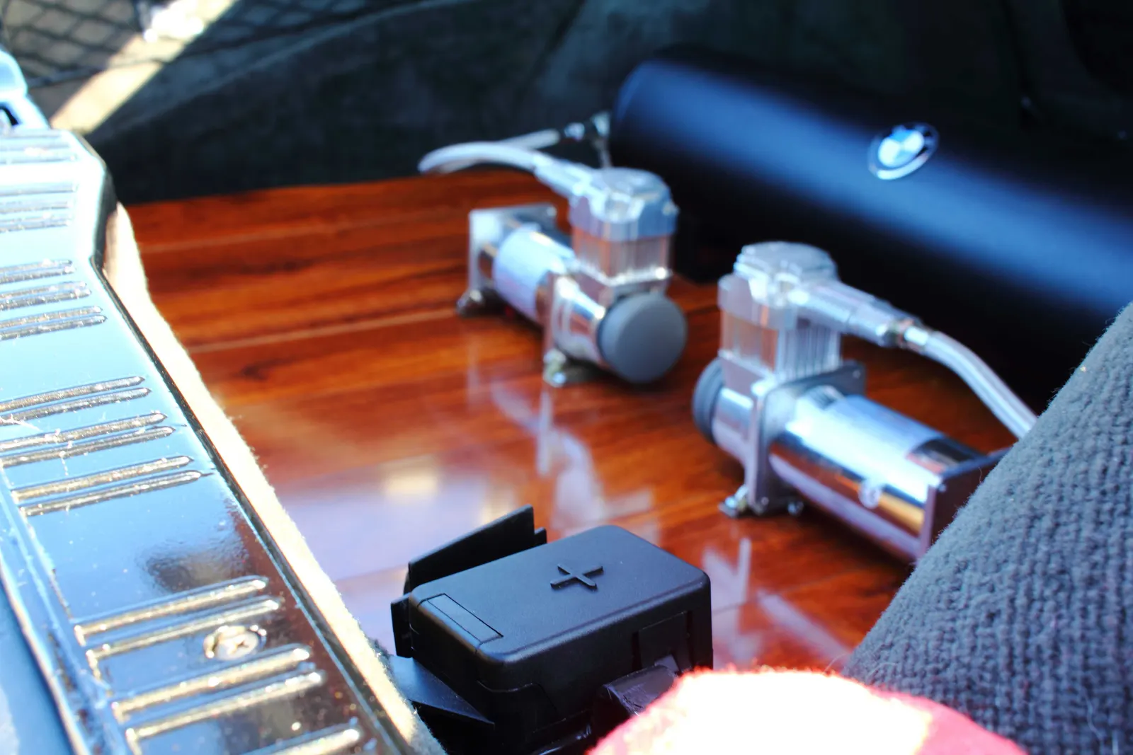 Close-up of twin chrome air-ride compressors mounted on a polished wood trunk floor