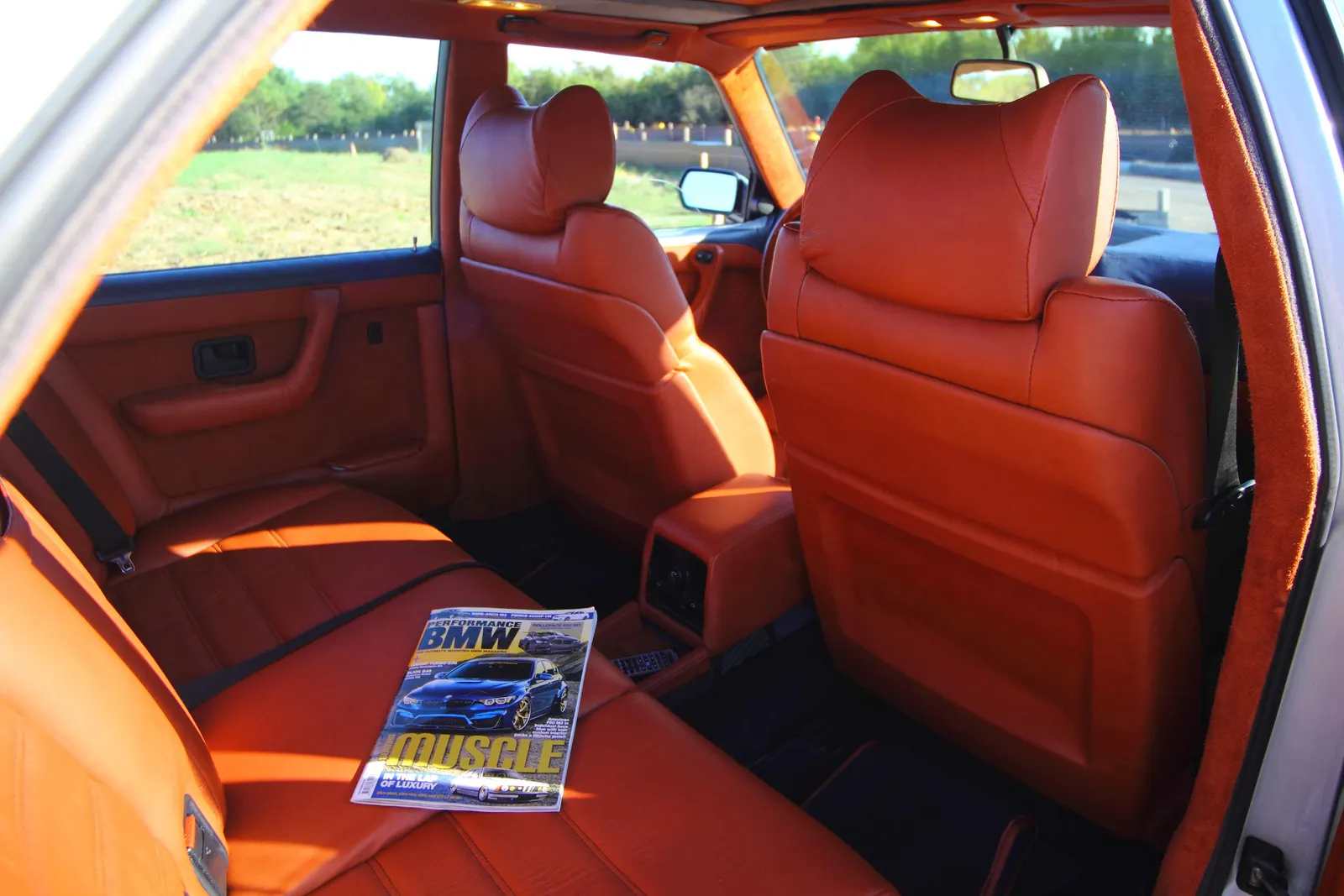 Rear cabin of a BMW E23 trimmed in orange leather